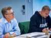 Zwei Männer sitzen an einem Tisch und arbeiten an ihren Unterlagen