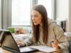 Eine Frau sitzt an einem Schreibtisch und schaut konzentriert auf ihren Laptop